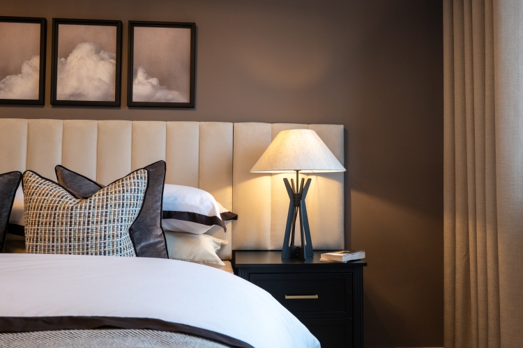 Beautifully made bed and bedside table with book and lamp.